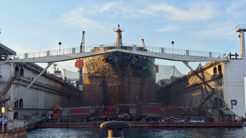The Ocean Melody in dry dock at the Qingdao yard, with firefighting equipment staged on the pier. Photo: The Paper