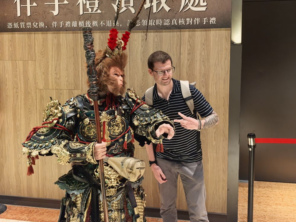 A fan poses with a Wukong mascot beside the souvenir counter at the Taipei venue. Photo: The Paper