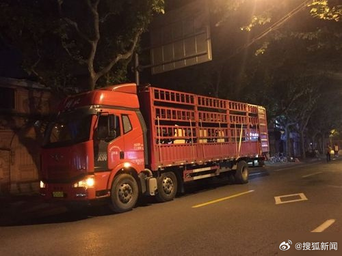 A heavy truck bedded down for the night on a lit urban street, its cargo bed stacked with foam boxes. Photo: @搜狐新闻