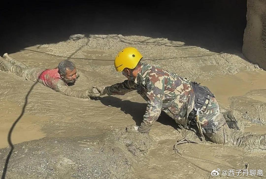 A rescuer reaches a person submerged in mud during the disaster response. Photo: @西子丹聊斋