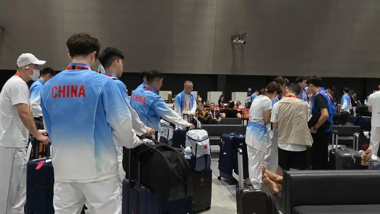 Members of the Chinese delegation, "CHINA" on their jackets, wait among the luggage. Photo: @新浪新闻