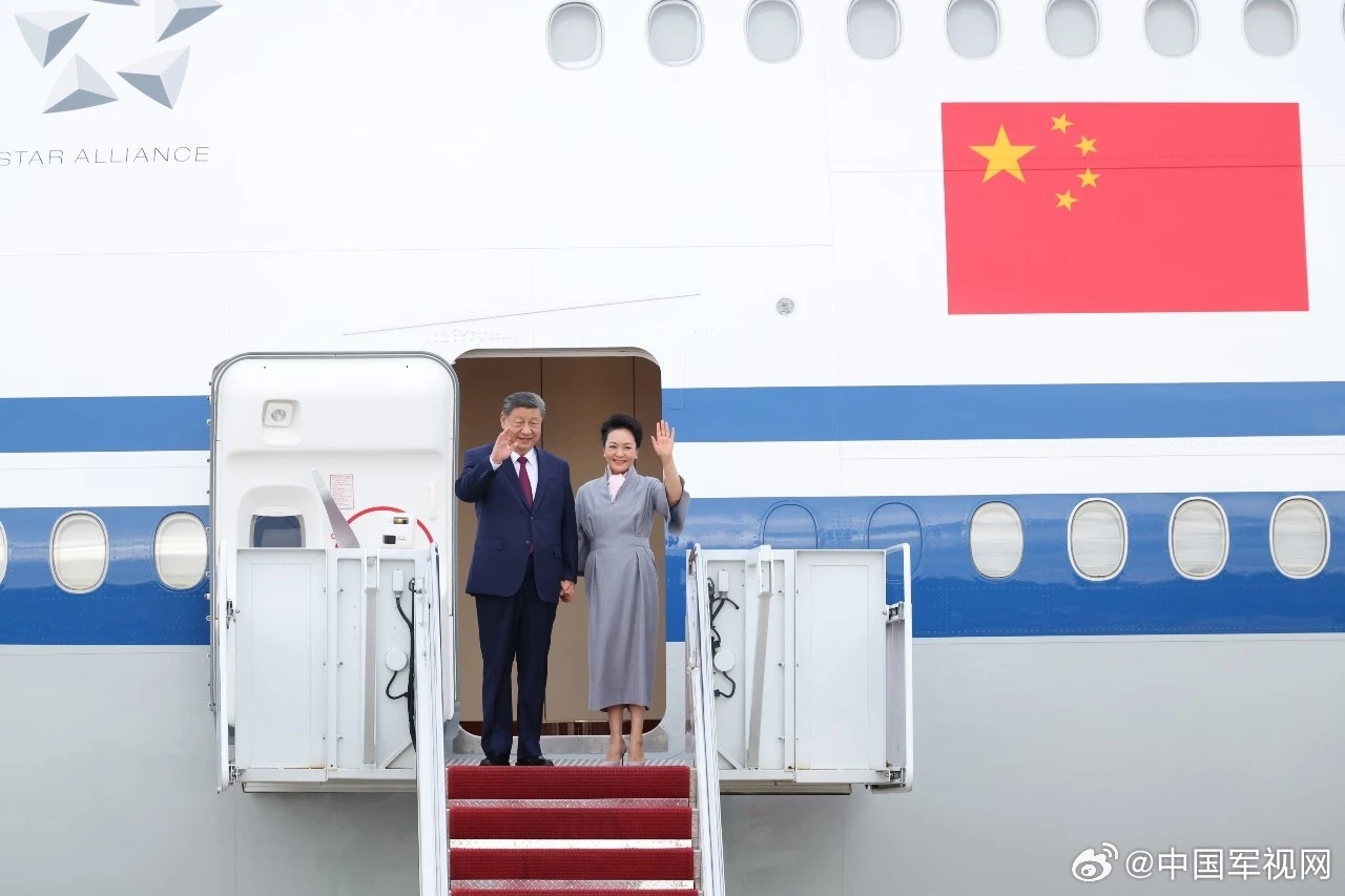 Xi and his wife Peng Liyuan wave from the door of their aircraft on arrival. Photo: @中国军视网