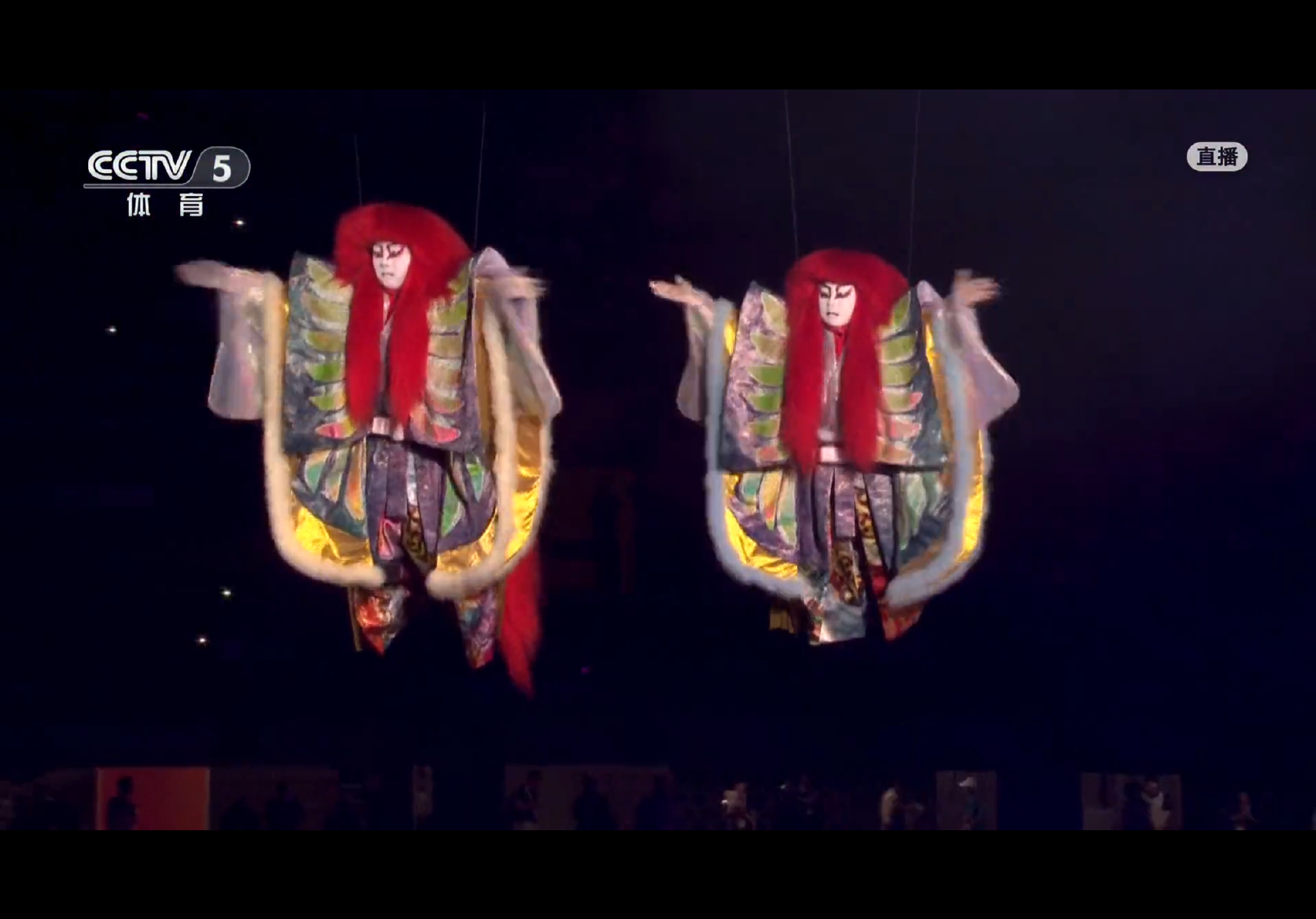 Two white-faced puppet figures with long red hair hover over the stage during the Nagoya ceremony broadcast. Photo: @草莓牛奶特别甜