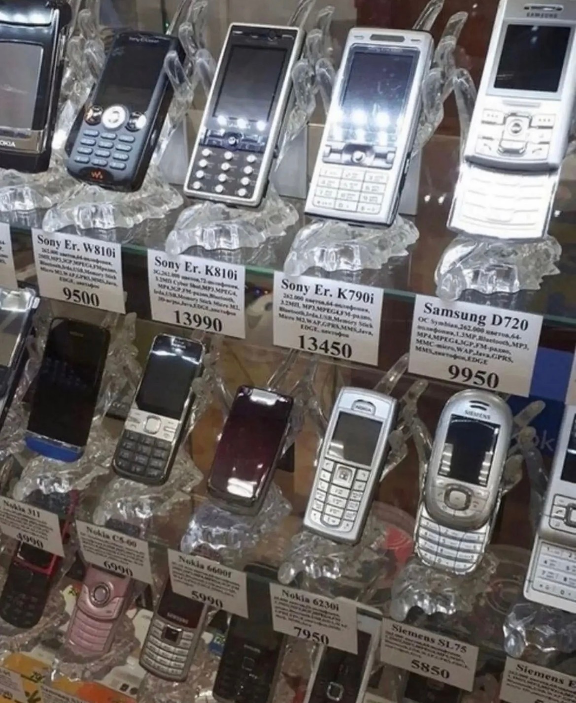 Feature phones of the 2000s — Sony Ericsson, Nokia, Siemens — on a secondhand-shop shelf. Photo: @-重启按钮-
