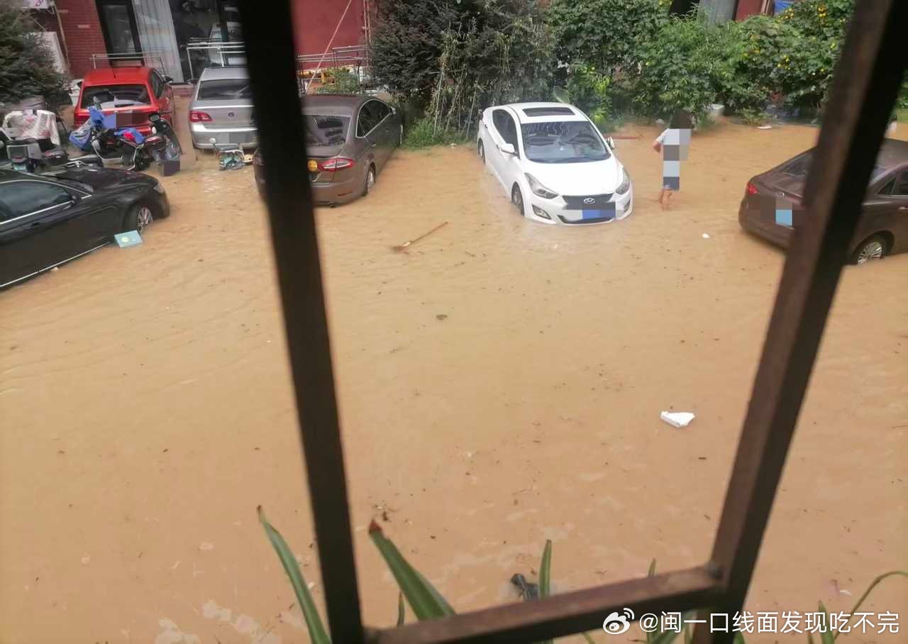 A flooded street in Ningde, with cars half-submerged and a resident wading through brown water. Photo: @闽一口线面发现吃不完