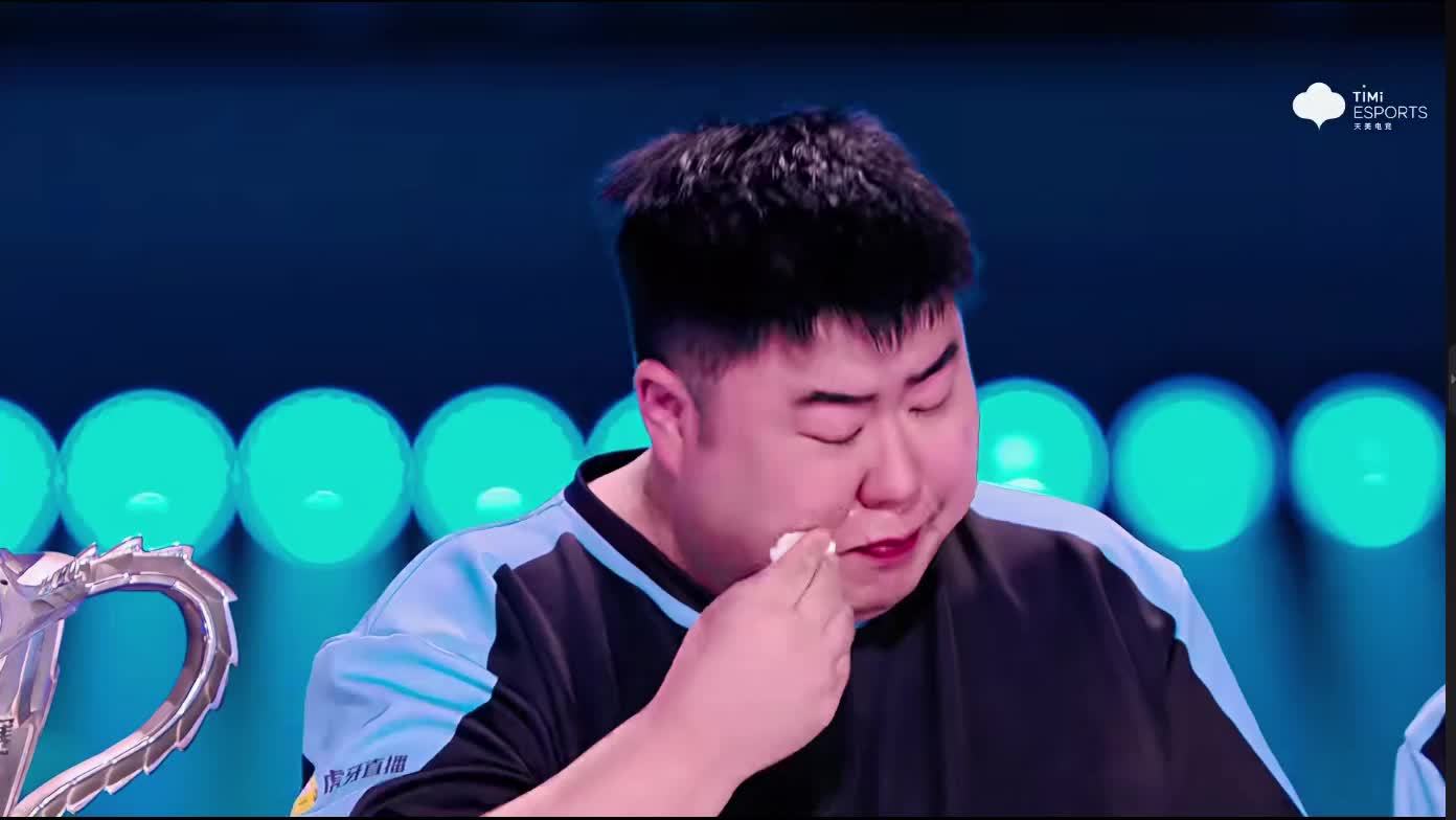 Xiao Pang wipes his eyes during the post-match interview, the trophy still on stage beside him. Photo: @角落猫M