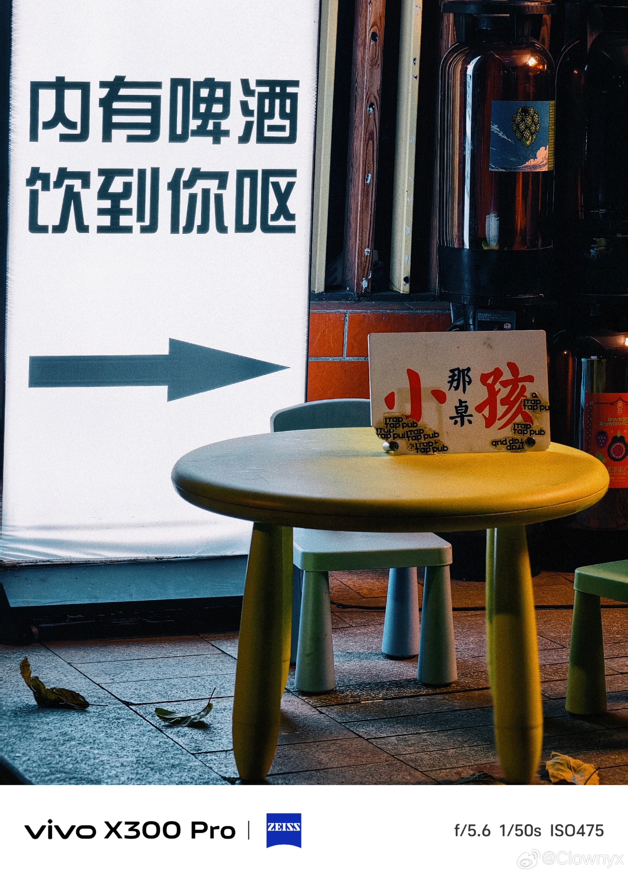 Street-side seating at night: a plastic table and folding chairs outside a storefront, the low-cost setting for an evening around a table. Photo: @Clownyx
