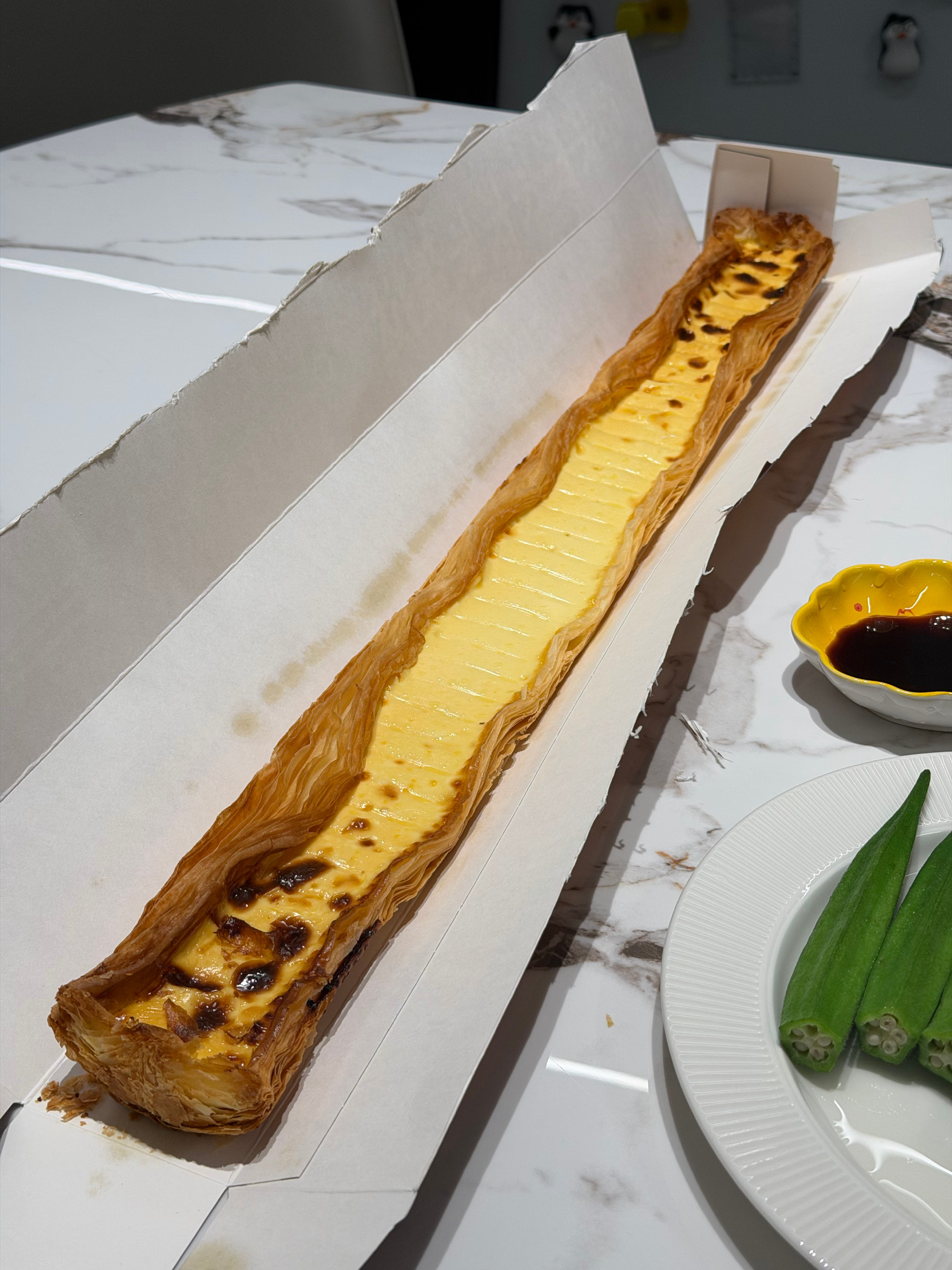 A super-long egg tart in its box: golden crust, a long shallow strip of custard, and a lot of pastry. Photo: @一个东海海海